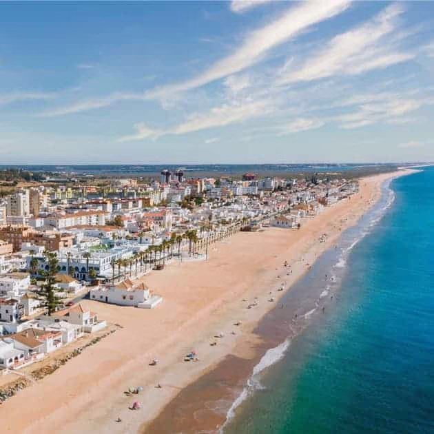 Vue aérienne des plages de Huelva avec des bâtiments côtiers et une mer d’un bleu profond