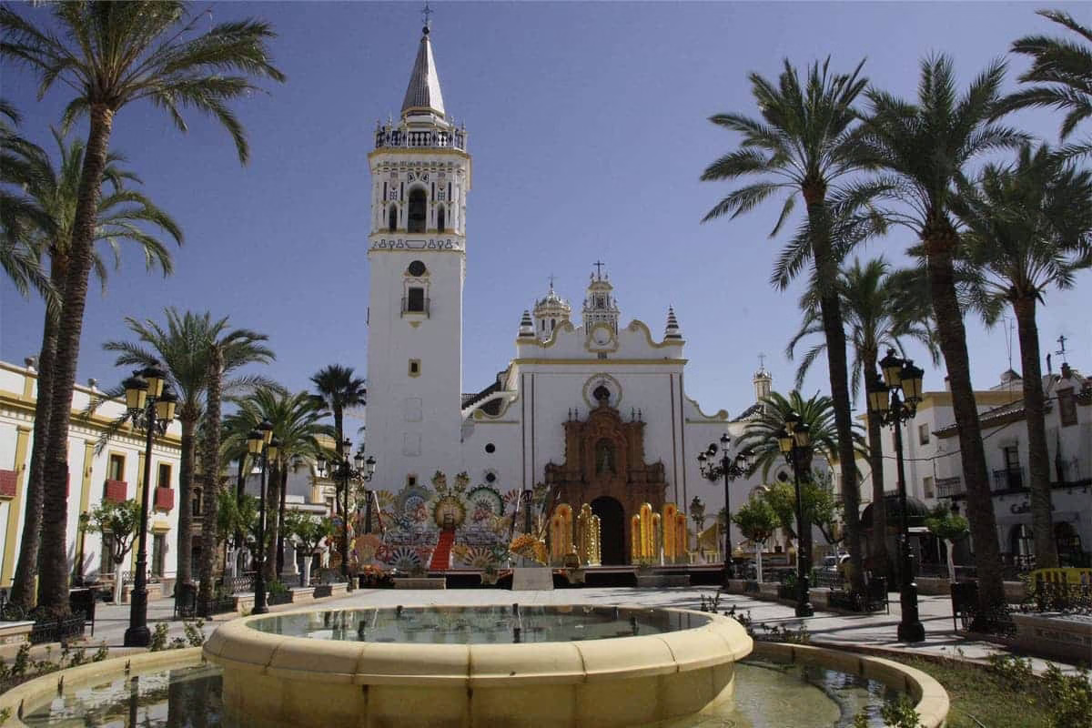 Place centrale de Huelva avec son église emblématique entourée de palmiers et d'une fontaine