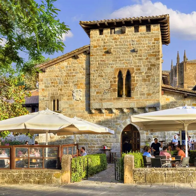 Pampelune2 Terrasse de restaurant avec parasols devant un bâtiment en pierre historique