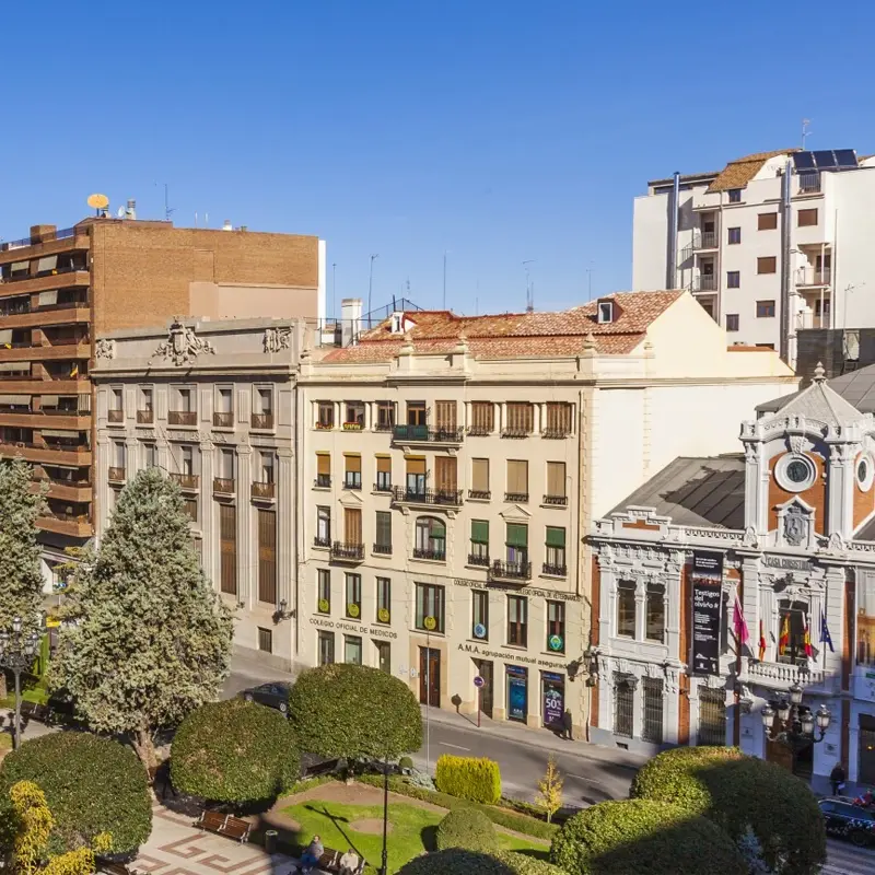 Albacete Vue sur des bâtiments anciens et modernes autour d’un petit parc urbain