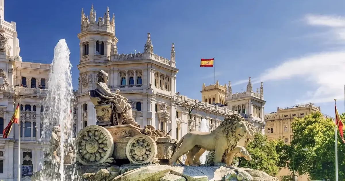 Plaza de Cibeles à Madrid avec la fontaine emblématique de la déesse Cybèle entourée de lions, bâtiments historiques et ciel bleu en arrière-plan