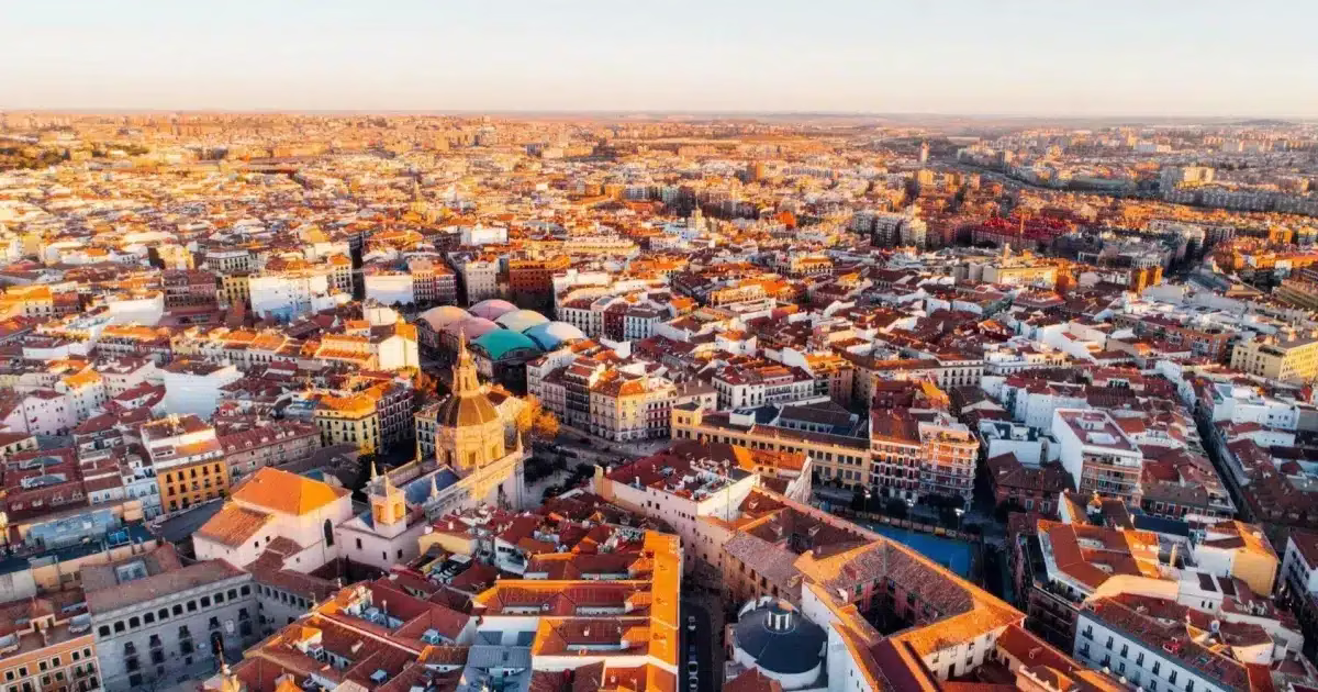Madrid vue de haut, panorama Vue panoramique aérienne de Madrid au coucher du soleil, mettant en valeur les toits rouges et l'architecture dense du centre-ville historique.