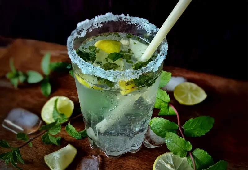 Verre de mojito avec citron vert, menthe et sucre givré, représentant un cocktail rafraîchissant en Espagne